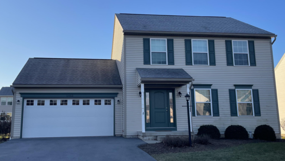 a two story house with green shutters and a white garage