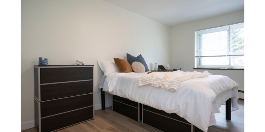 a bedroom with a bed, dresser and window