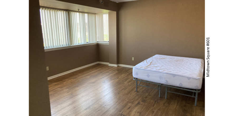 an empty bedroom with a bed and a window