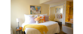 a bedroom with a white bed and a yellow blanket