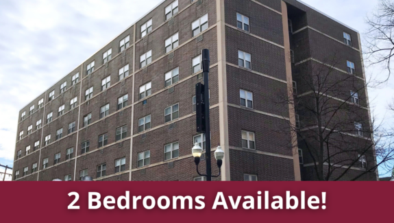 a tall brick building with windows and a red sign that says 2 bedroom available