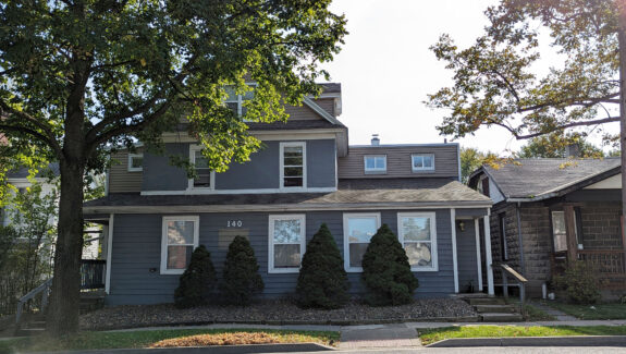 a gray house with trees in front of it