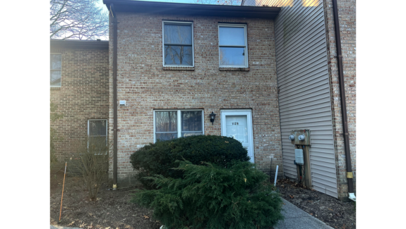 a brick building with a white door and three windows