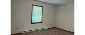 an empty room with a window and a radiator
