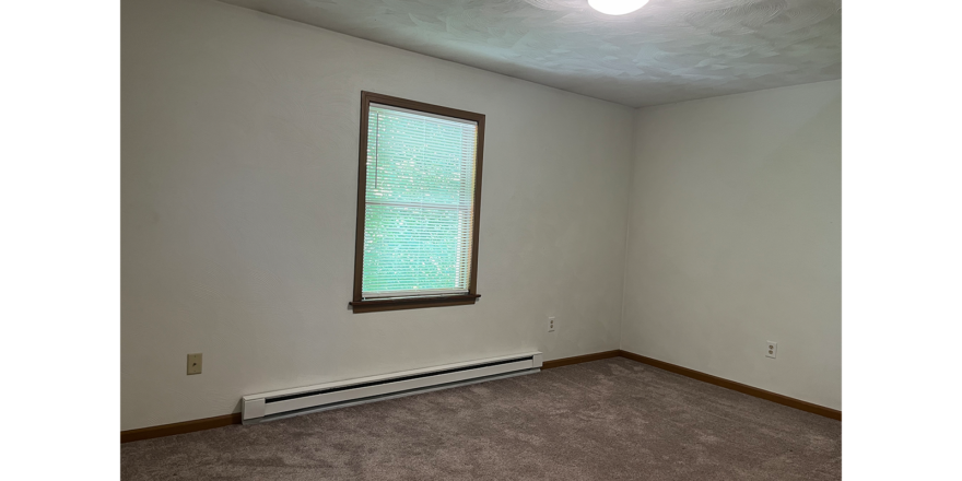 an empty room with a window and a radiator