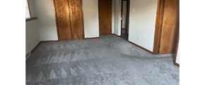 an empty room with gray carpet and wooden doors leading to a closet, washer dryer, and bedroom