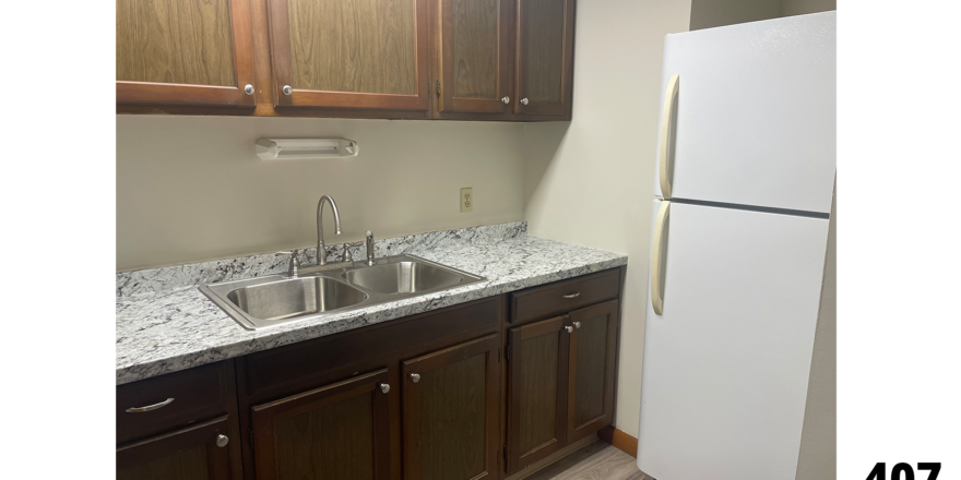 a kitchen with gray LVP, a white refrigerator freezer, and a kitchen sink