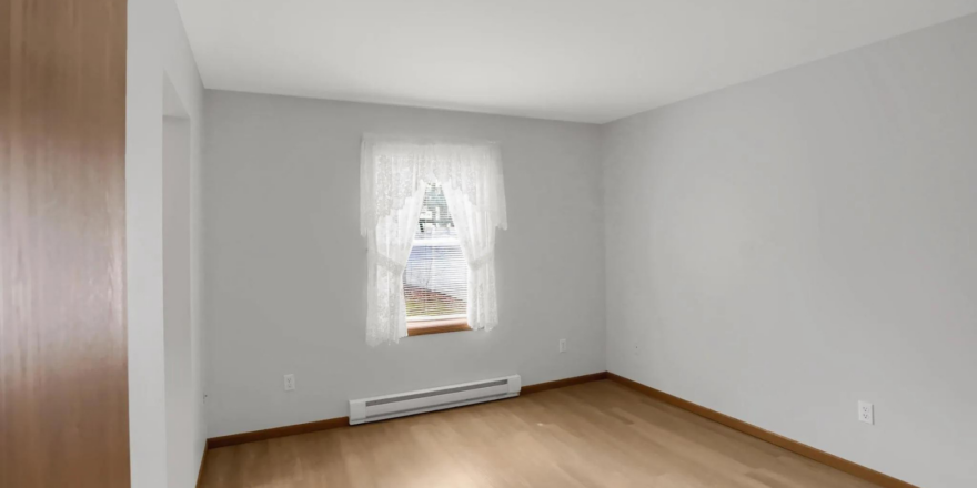 an empty room with wood floors and a window