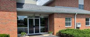 brick building with glass windows and a parking lot in front of it