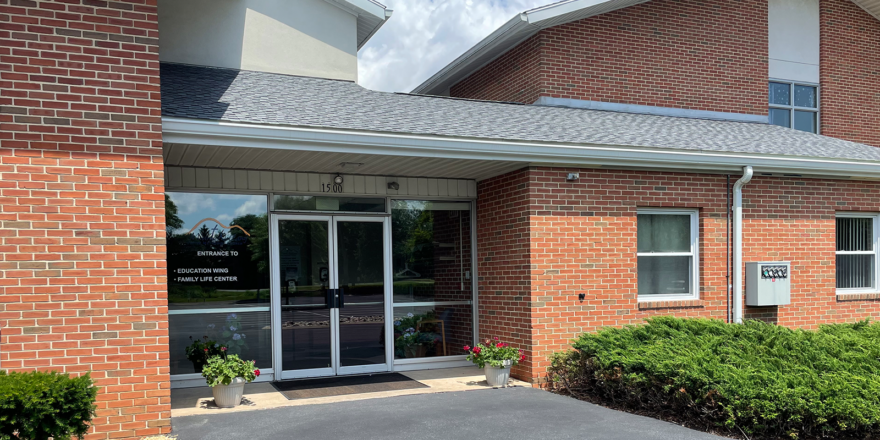 brick building with glass windows and a parking lot in front of it