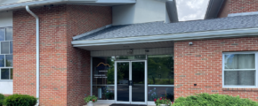 brick building with glass windows and a parking lot in front of it