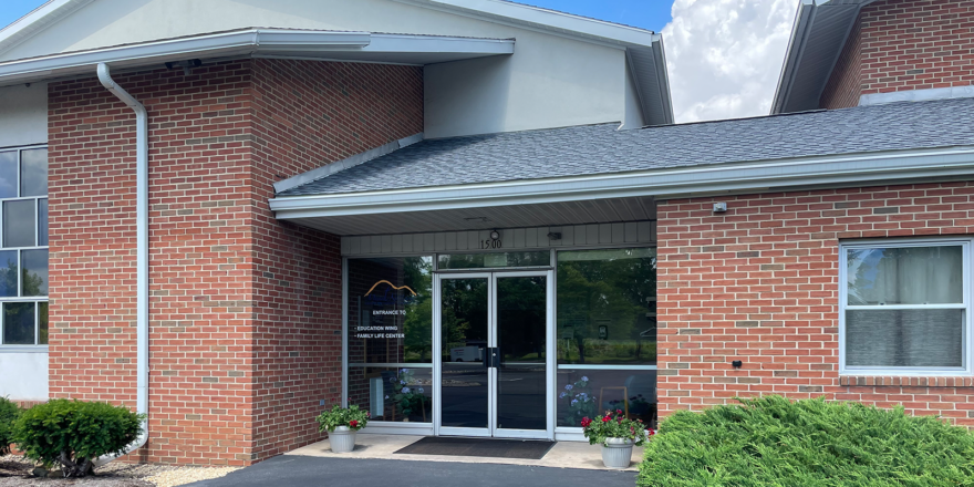 brick building with glass windows and a parking lot in front of it