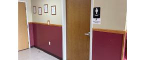 a hallway with two doors and a bathroom sign on the wall