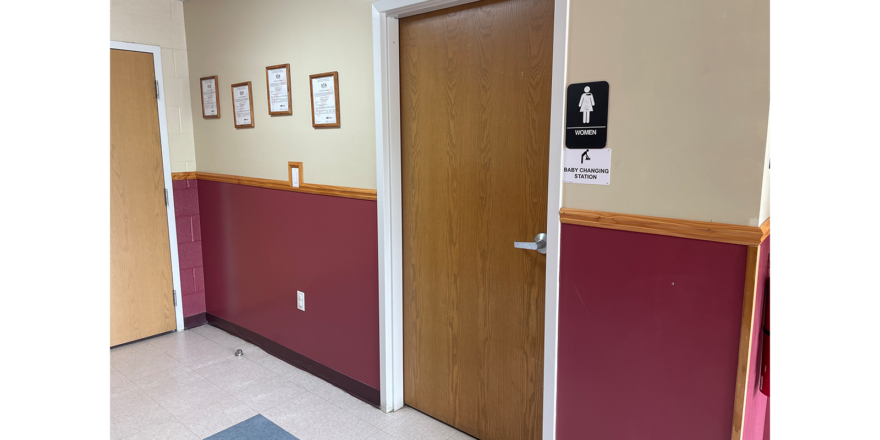 a hallway with two doors and a bathroom sign on the wall