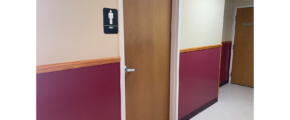 a hallway with two doors and a bathroom sign on the wall