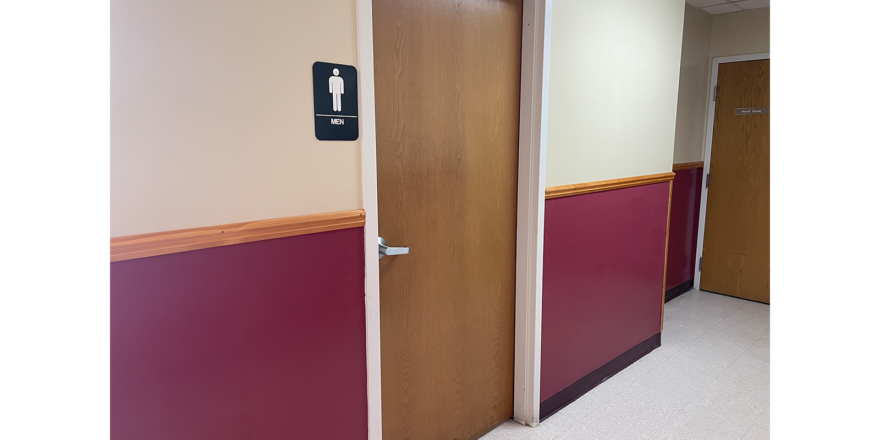 a hallway with two doors and a bathroom sign on the wall