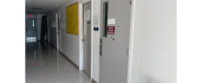 a long hallway with two doors and a yellow sign on the wall