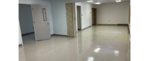 an empty room with 3 doorways , white walls, overhang lights, and white tile