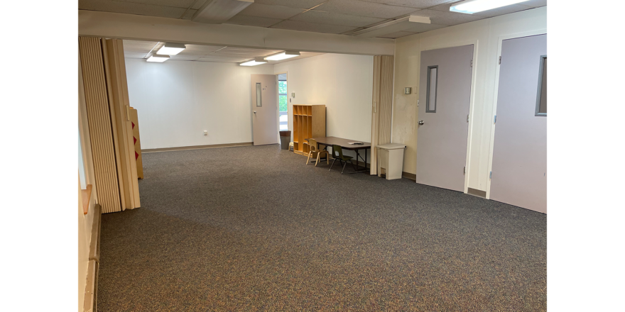 an empty room with gray carpet, 2 doors, lights, and white walls