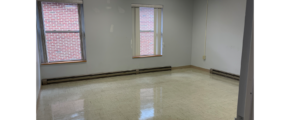 an empty room with 3 windows, white walls, overhang lights, and white tile