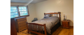 a bedroom with a bed, dresser and window