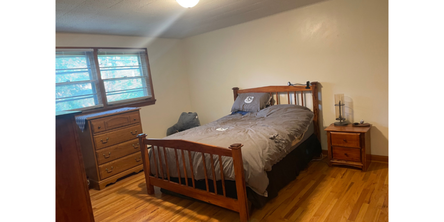 a bedroom with a bed, dresser and window