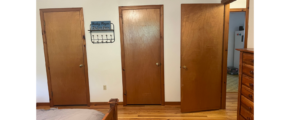 a bedroom with wooden floors and three doors