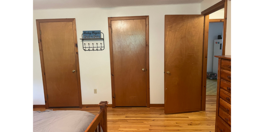 a bedroom with wooden floors and three doors