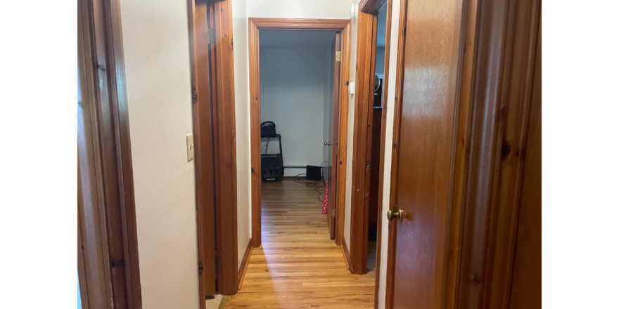 a hallway with wooden doors and hard wood floors