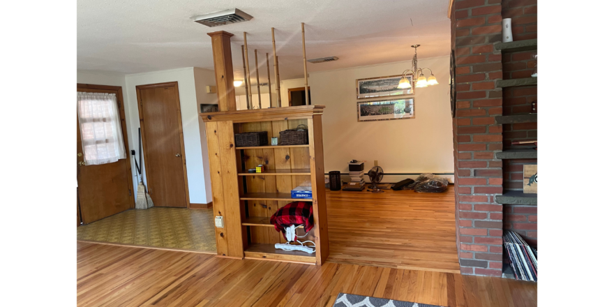 a living room with wood floors and a brick fireplace