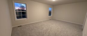 an empty room with carpet and two windows