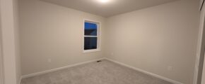 an empty room with a window and carpet