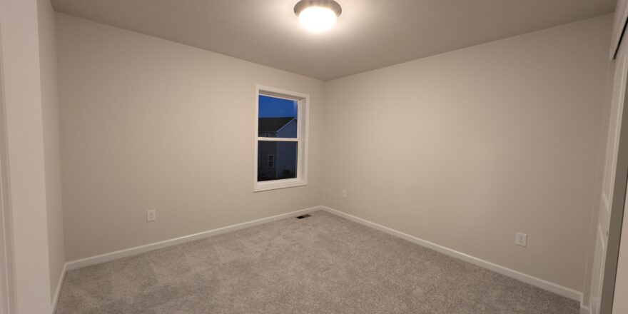 an empty room with a window and carpet