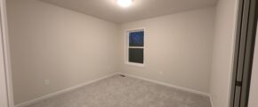 an empty room with a window and carpeted floor