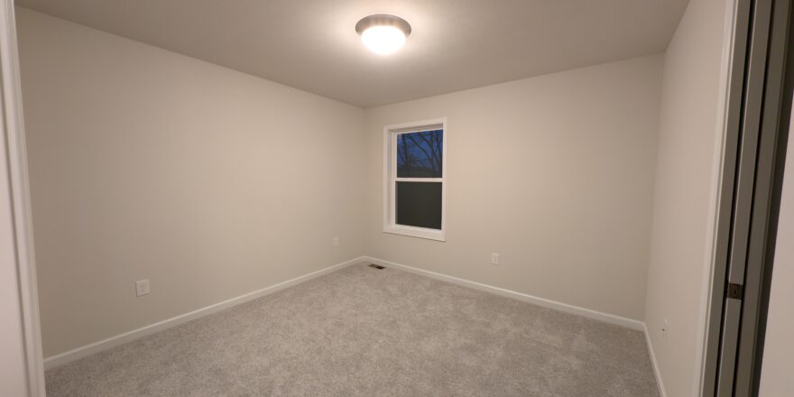 an empty room with a window and carpeted floor