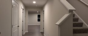 a long hallway with stairs and a clock on the wall