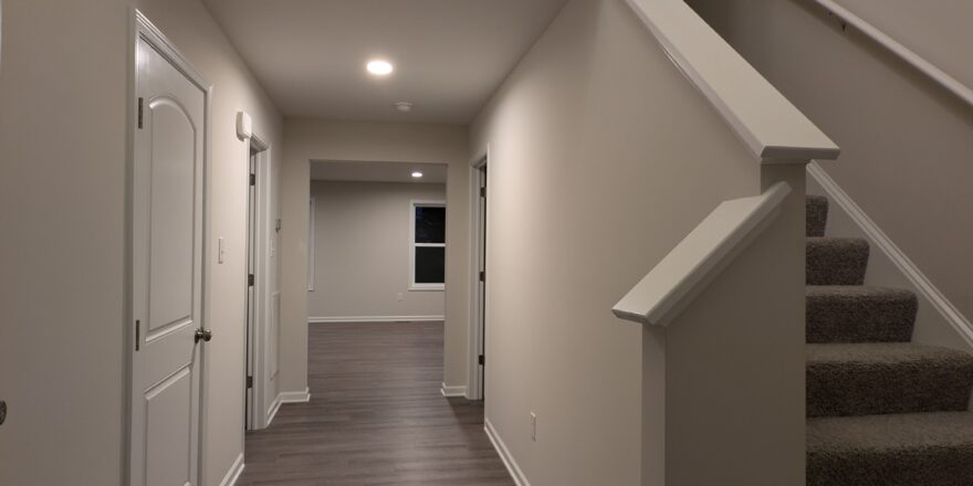 a long hallway with stairs and a clock on the wall