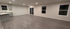 an empty room with a counter, cabinets, and windows