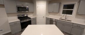 a kitchen with white counter tops and gray cabinets