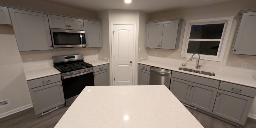 a kitchen with white counter tops and gray cabinets