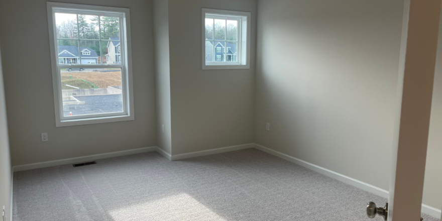 an empty room with two windows and a door