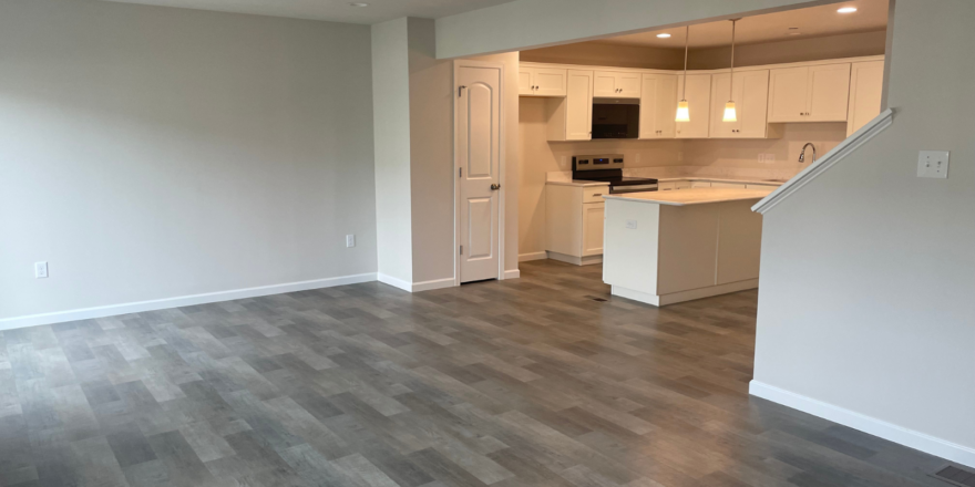 an empty living room with wood floors and white cabinets